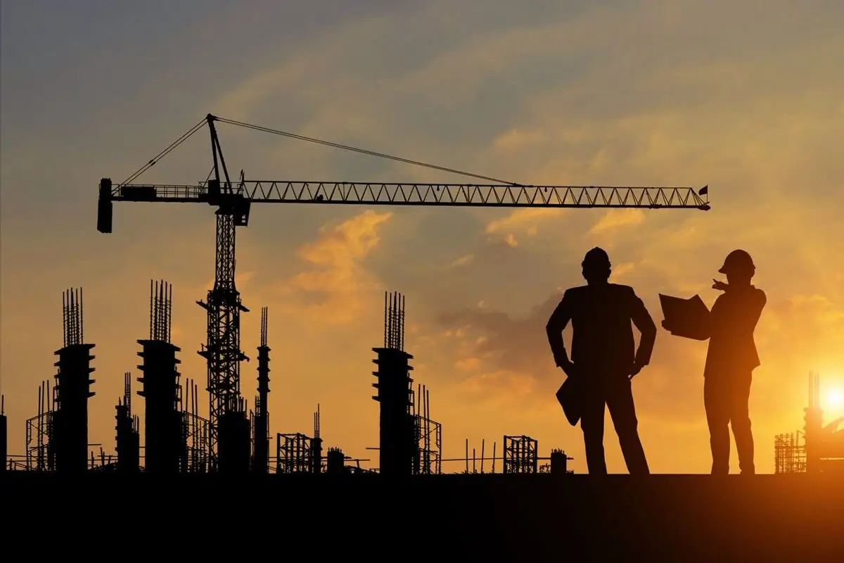 Construction site with multiple cranes, workers, and high-rise buildings under development.
